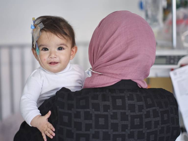 Online-Spenden Eine kleine Patientin wird von ihrer Mama gehalten