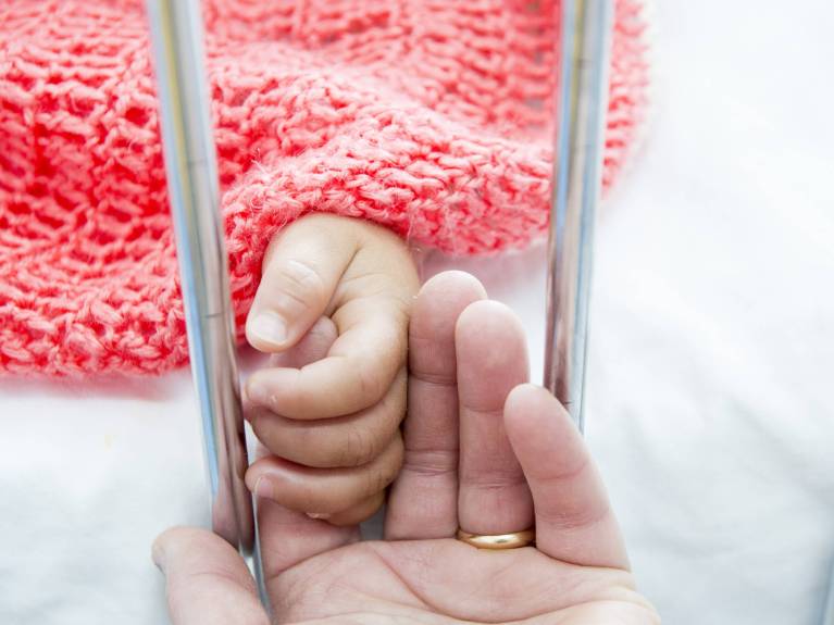 Was bleibt - Testamentsspenden Eine ältere Hand und eine kleine Babyhand halten sich