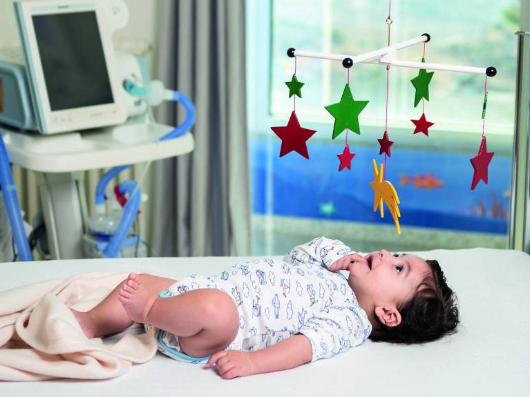 Patenschaft Symbolbild Ein Baby liegt unter einem Sternen-Mobile im Caritas Baby Hospital