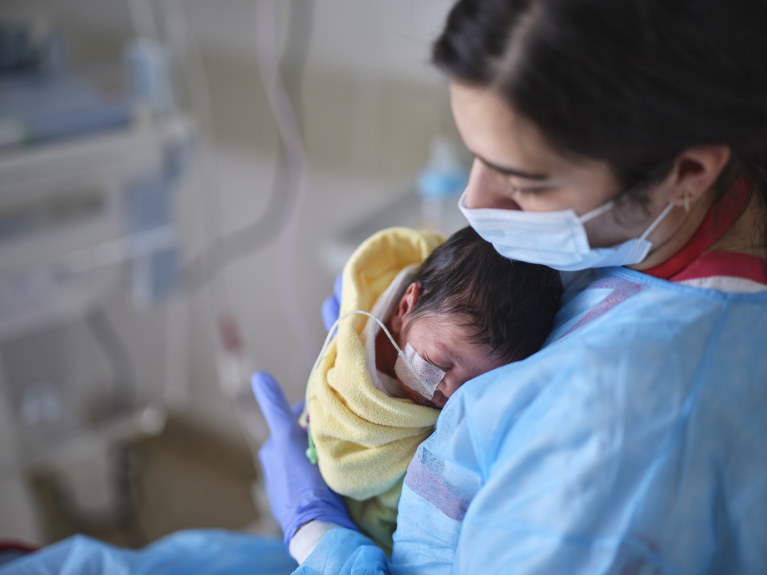 Ein Baby auf dem Arm einer Ärztin, die langfristige Hilfe durch das Pate werden gibt Familien Stabilität