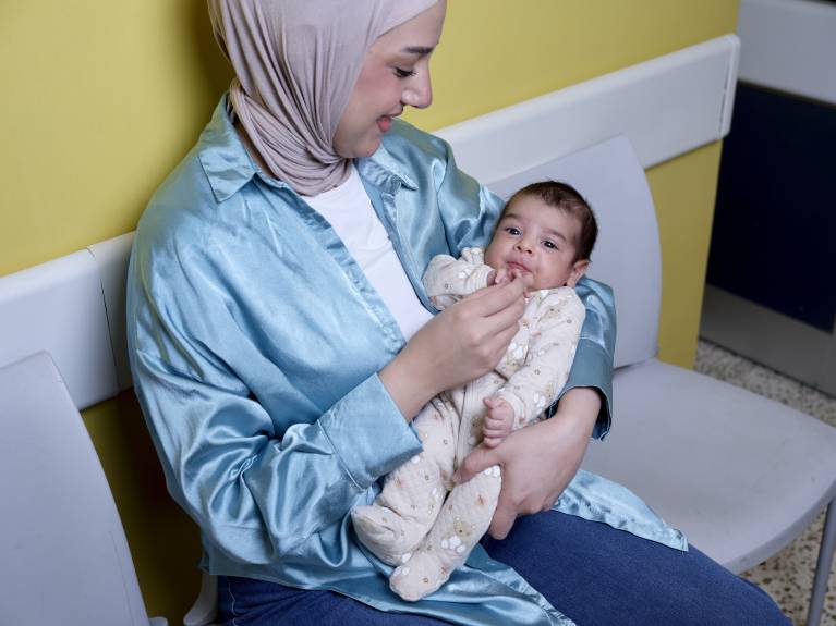 Eine Mutter hält ihr Baby, genau so wie eine Patenschaft die Eltern stärkt