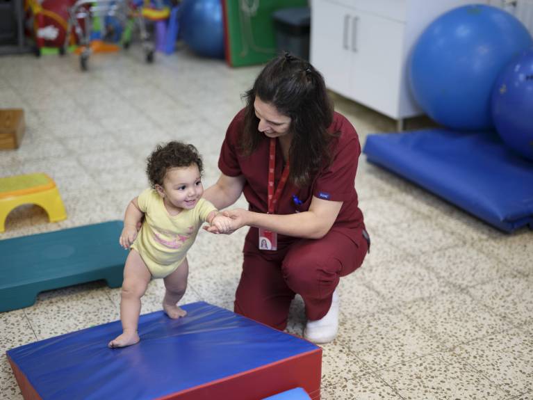 Ein Kind bekommt Unterstützung in der Physiotherapie